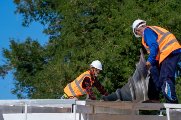 The Roofer technicians work and installing new roof structure on top roof of house,metal roof,fasteners corrugated sheets.